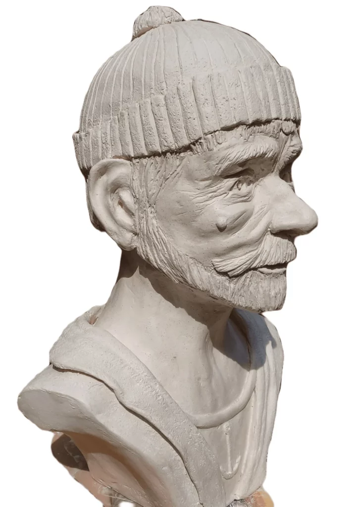 Buste sculpté en argile représentant un marin portant un bonnet, vu de profil.